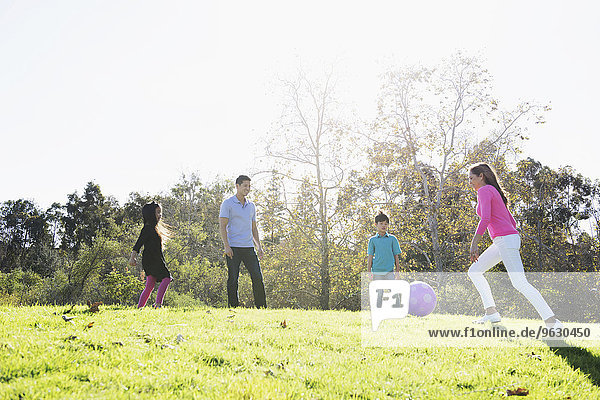 Mature couple and children playing soccer in park