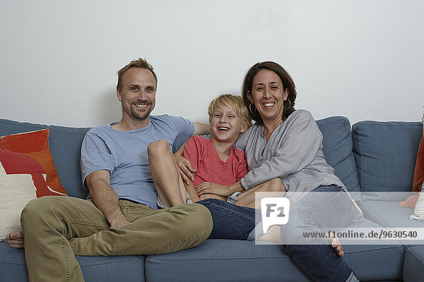 Eltern mit Sohn auf Sofa sitzend