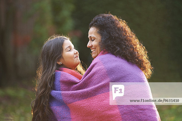 Mutter und Tochter im Garten in Decke gehüllt