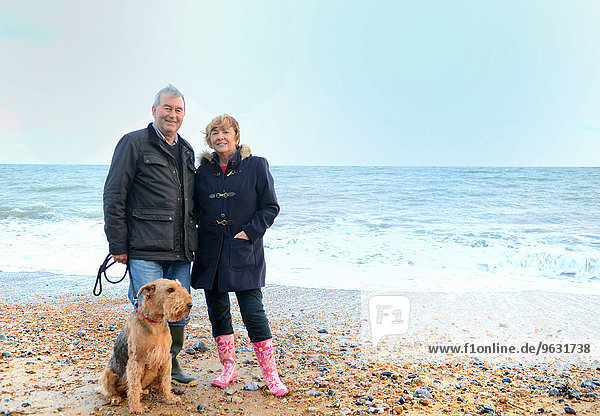 Porträt eines älteren Paares mit Hund am Strand