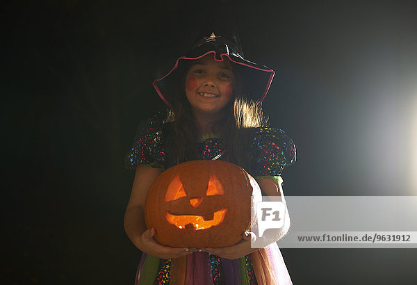 Porträt eines Mädchens in Halloween-Hexenkostüm mit Kürbis