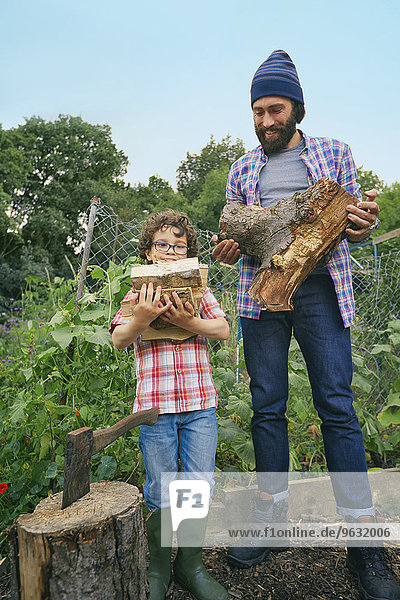 Father and son with chop logs on allotment