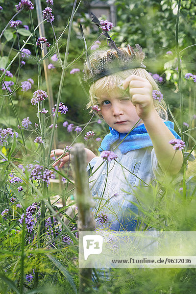 Junge verkleidet und spielend mit Pflanzen im Garten