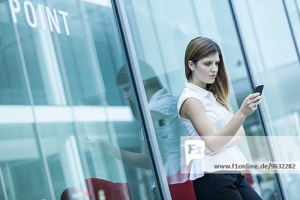Woman using smartphone against glass window