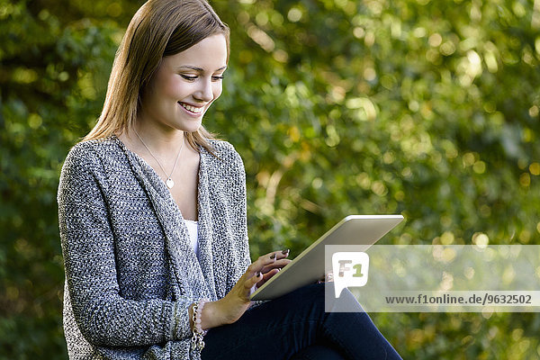 Junge Frau mit Touchscreen auf digitalem Tablett im Park