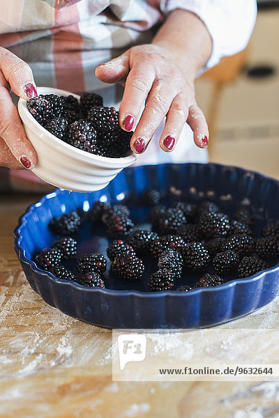 A woman pouring fresh blackberries into a dish.