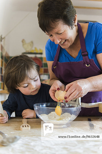 A woman and a child cooking at a kitchen table  making fairy cakes.