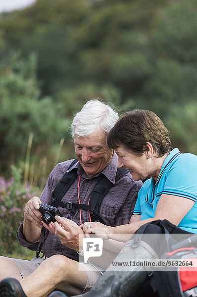 A mature couple taking photographs while out walking.