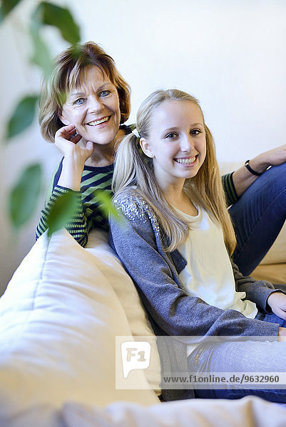 Grandmother and granddaughter relaxing on couch  smiling  portrait