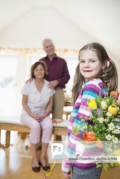 Granddaughter handover bouquet to her grandmother and grandfather in background