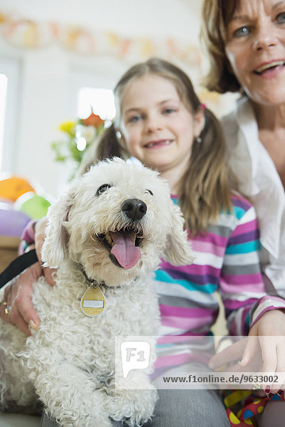 Portrait of grandmother and grandchild with dog in living room  smiling