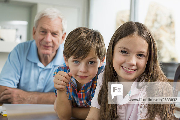 Children doing homework with their grandfather