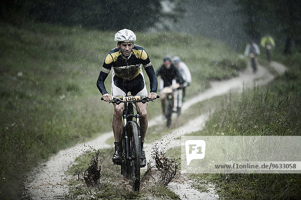 Mountain bikers riding in rain through mud  Italy