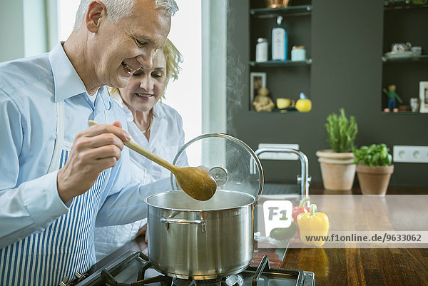 Mature couple preparing food in kitchen  smiling