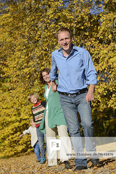 Family walking in autumn leaves  smiling