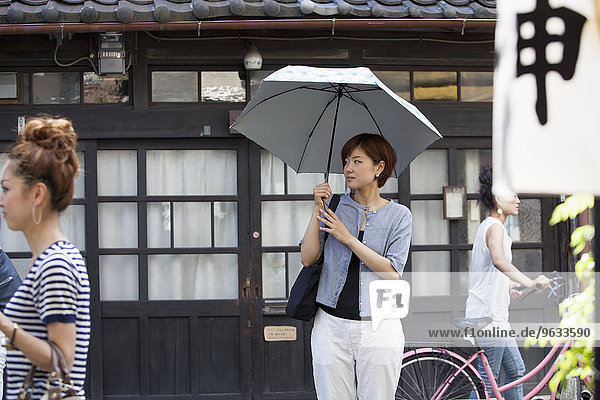 Woman standing outdoors  holding an umbrella.