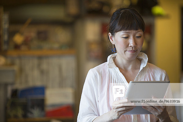 Woman standing in a cafe  holding a digital tablet.