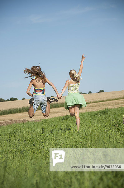 Two carefree happy young girls running field