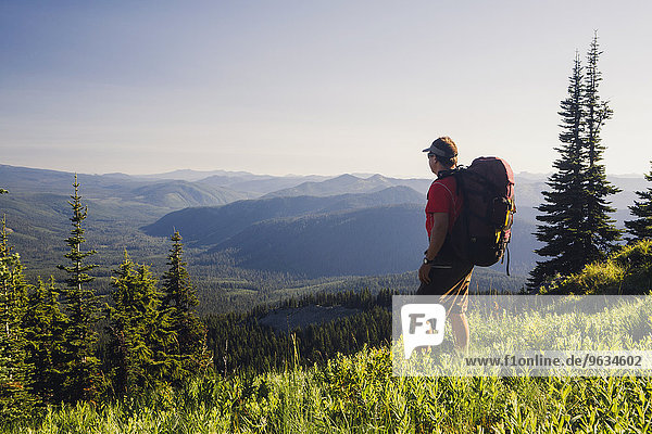 Man backpacking in the mountains  walking on a ridge overlooking a valley.
