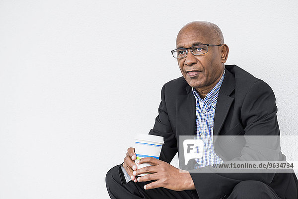 African businessman sitting drinking Coffee to go