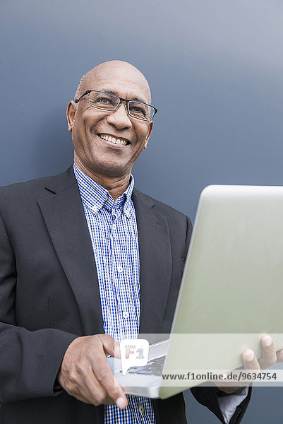 Happy African businessman holding laptop computer
