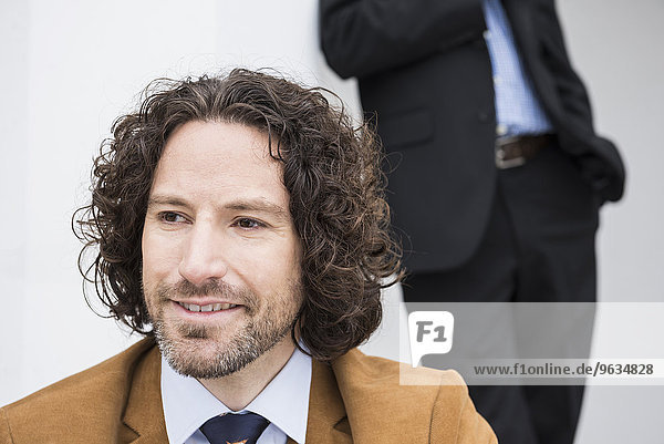 Portrait smiling young businessman suit long hair