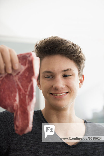 Young man looking at ham in kitchen