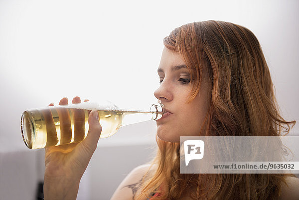 Young red-haired woman drinking beer from the bottle