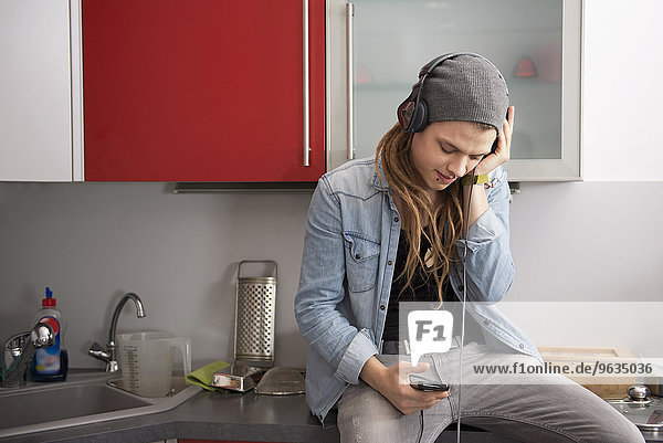 Young man with dreadlocks and piercing listening to music with headphones