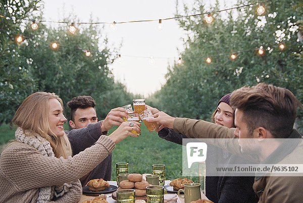 An apple orchard in Utah. Group of people toasting with a glass of cider  food and drink on a table.