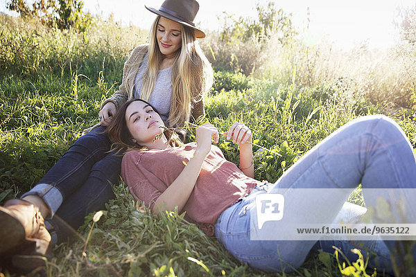 An apple orchard in Utah. Two women lying in the grass.