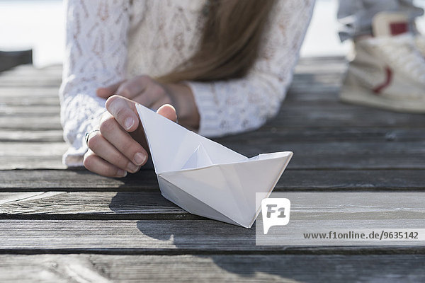 Close up woman holding paper boat wooden jetty