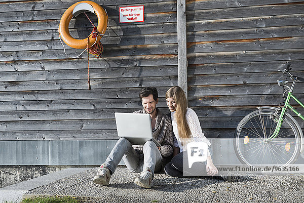 Wooden boathouse couple sitting using computer
