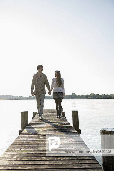 Young couple walking on wooden jetty