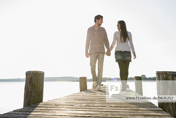 Romantic couple walking wooden jetty lake