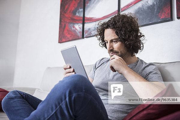 Man sitting on couch and using a digital tablet