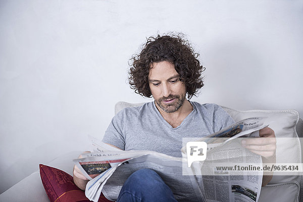 Man sitting on couch and reading a newspaper