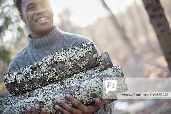 Man carrying firewood in forest in autumn.