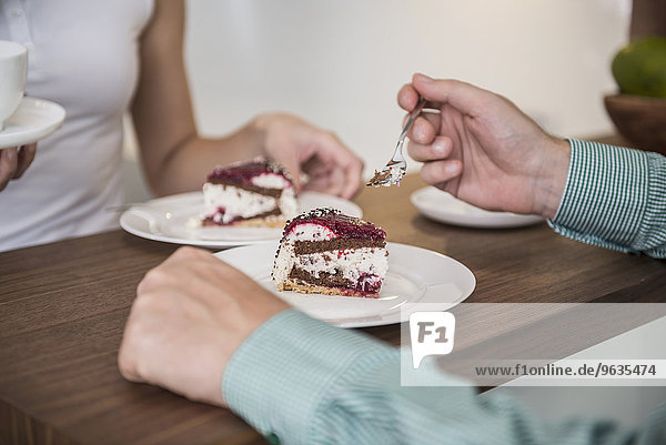 Couple eating slice of cake in a kitchen