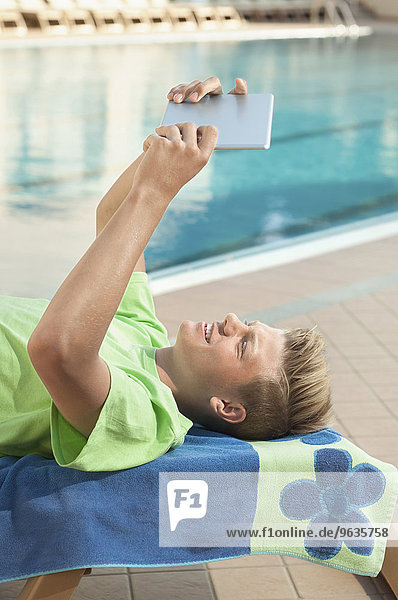 Boy swimming pool holding tablet computer holiday