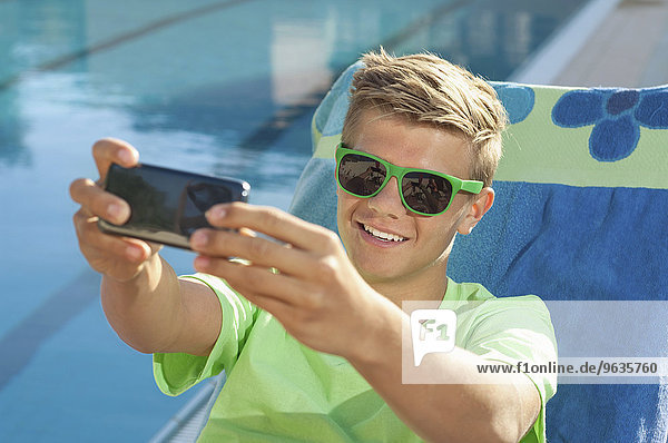 Teenager boy taking selfie picture swimming pool