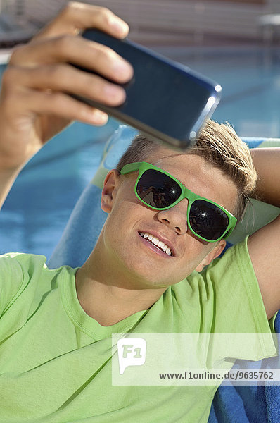 Teenager holding Smartphone taking self-portrait