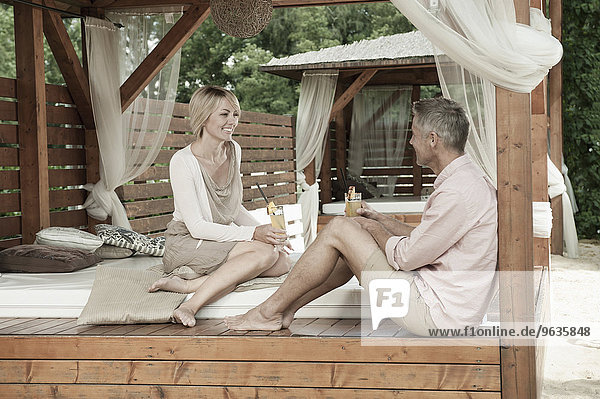 Couple chic sitting garden drinking cocktail happy
