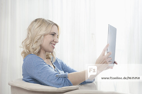 Attractive blond young woman chair tablet computer