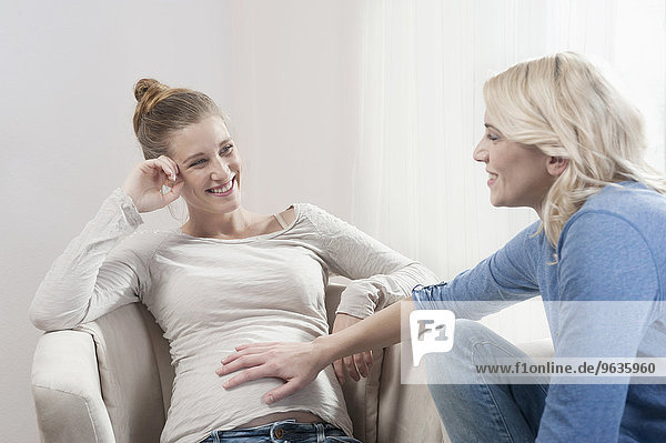 Pregnant woman girlfriend talking touching stomach