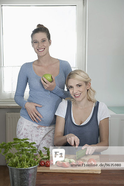 Young pregnant woman girlfriend kitchen salad