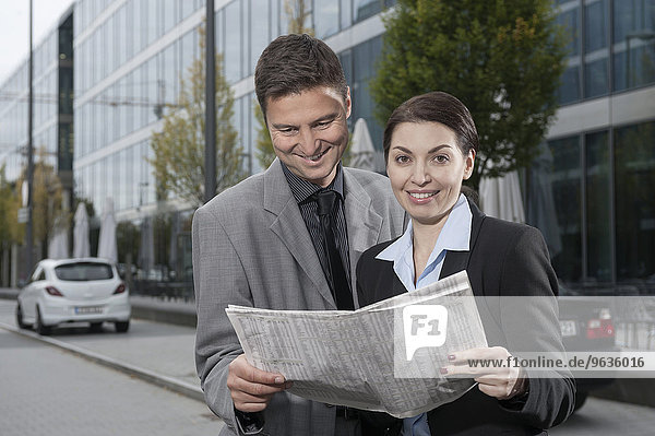 Business executives reading a financial newspaper and smiling