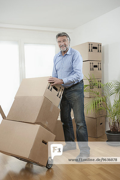 Senior man with moving boxes in new apartment