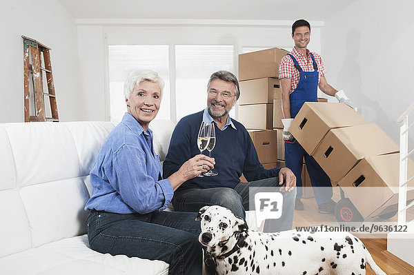 Senior couple celebrating moving to new house with champagne