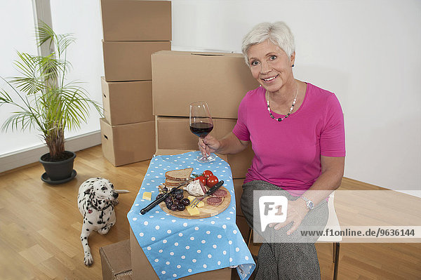 Senior woman moving into new home celebrating with wine